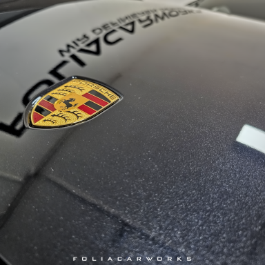 Porsche-Wappen auf einer glänzenden schwarzen Oberfläche.